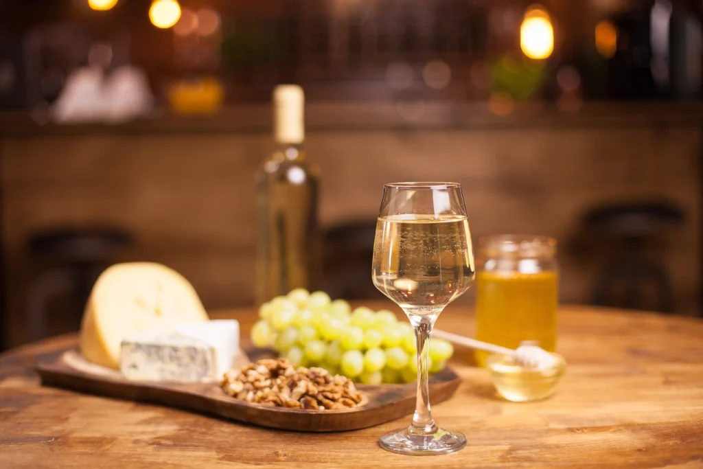 white wine glass with cheese and grapes
