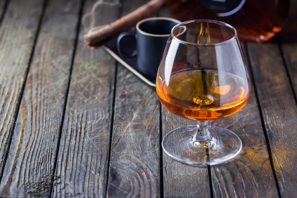 cognac glass with cigar on wooden table