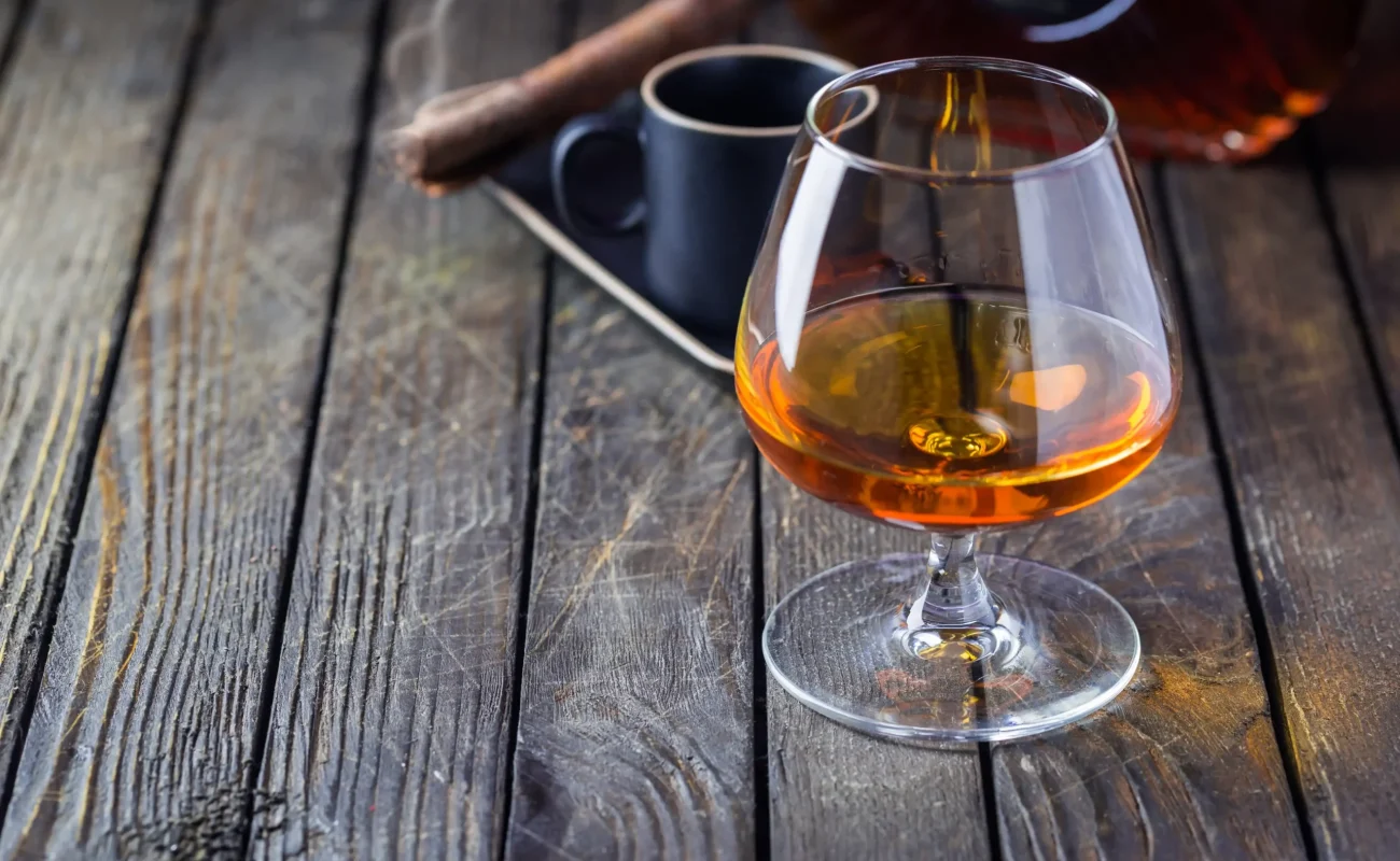 cognac glass with cigar on wooden table