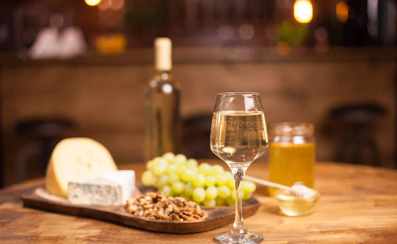white wine glass with cheese and grapes